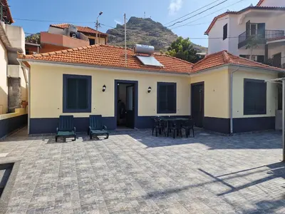 a house with a patio with chairs and a table at Machico Villas Accommodation with Private Parking in Machico