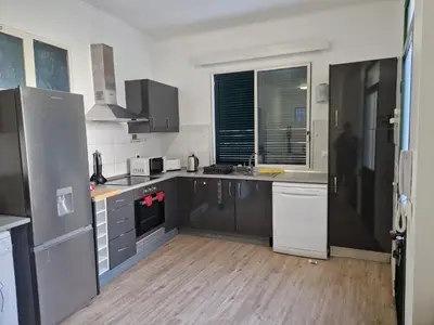 a kitchen with black and white appliances and a wooden floor at Machico Villas Accommodation with Private Parking in Machico