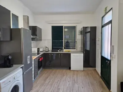 a kitchen with black and white appliances and wooden floors at Machico Villas Accommodation with Private Parking in Machico
