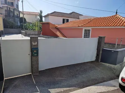 a white gate in front of a house at Machico Villas Accommodation with Private Parking in Machico