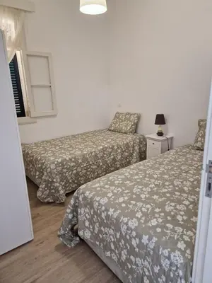 a bedroom with two beds and a window and a lamp at Machico Villas Accommodation with Private Parking in Machico
