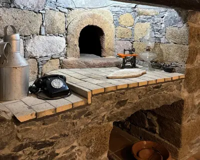 a stone kitchen with a stone wall with a stone oven at Boaventura Cottage-Casa de Campo in Serra de Água
