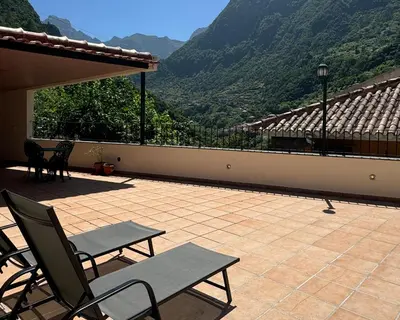 a patio with a table and chairs and a view of mountains at Boaventura Cottage-Casa de Campo in Serra de Água