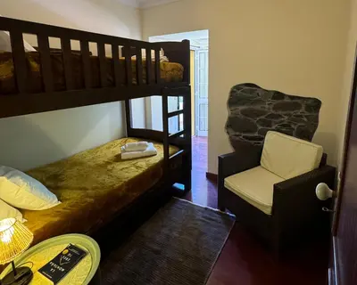 a bedroom with two bunk beds and a chair at Boaventura Cottage-Casa de Campo in Serra de Água