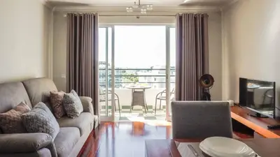 a kitchen with wooden cabinets and a table and chairs at Like Home VI Praia Formosa I Sea View Balcony I Free Parking in Funchal