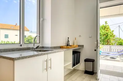 a kitchen with white cabinets and a large window at Casa da Tia Celeste I, a Home in Madeira in Ponta do Sol