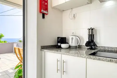 a kitchen with white cabinets and a view of the ocean at Casa da Tia Celeste I, a Home in Madeira in Ponta do Sol