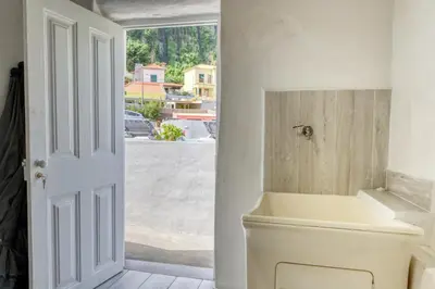 a white bathroom with a toilet and a window at Casa da Tia Celeste I, a Home in Madeira in Ponta do Sol
