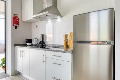 a kitchen with white cabinets and a stainless steel refrigerator at Casa da Tia Celeste I, a Home in Madeira in Ponta do Sol