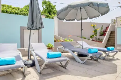 a patio with two lounge chairs and an umbrella at Casa da Tia Celeste II, a Home in Madeira in Ponta do Sol