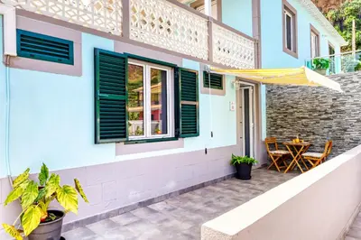 a patio of a house with a table and a yellow umbrella at Casa da Tia Celeste III, a Home in Madeira in Ponta do Sol
