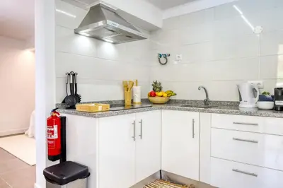 a kitchen with white cabinets and a red fire extinguisher at Casa da Tia Celeste III, a Home in Madeira in Ponta do Sol