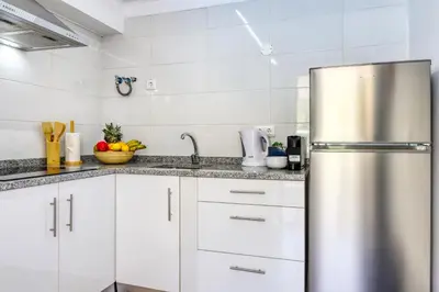 a kitchen with white cabinets and a stainless steel refrigerator at Casa da Tia Celeste III, a Home in Madeira in Ponta do Sol