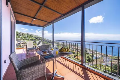 a balcony with a table and chairs and the ocean at Casa do Miradoro in Santa Cruz
