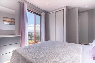 a bedroom with a bed and a large window at Casa do Miradoro in Santa Cruz