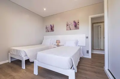 two beds in a room with white walls and wooden floors at Casa do Miradoro in Santa Cruz