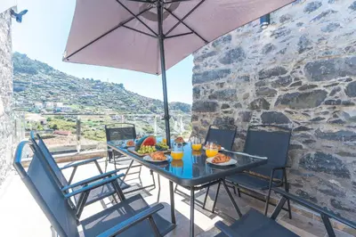 a table with food and an umbrella on a balcony at Julianas House 1 by Atlantic Holiday in Campanário