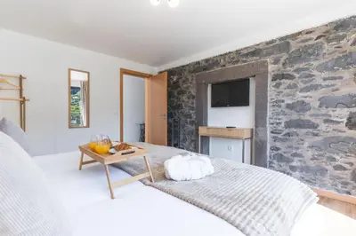 a bedroom with a stone wall with a bed and a table at Julianas House 1 by Atlantic Holiday in Campanário