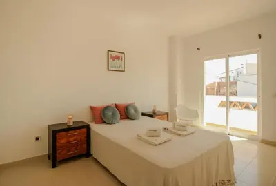 a white bedroom with a bed and a window at FLH Budens Duplex with Terrace in Vila do Bispo