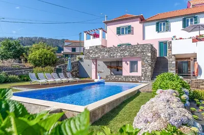 a villa with a swimming pool and a house at Casa das Orquideas in Estreito da Calheta