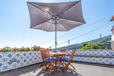 a table and chairs with an umbrella on a balcony at Casa das Orquideas in Estreito da Calheta