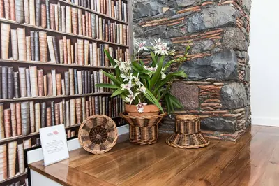 a table with a vase of flowers and books at Casa das Orquideas in Estreito da Calheta