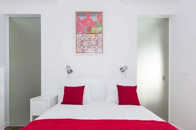a bedroom with a white bed with red pillows at Casa das Orquideas in Estreito da Calheta
