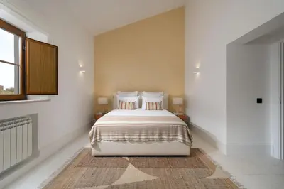 a bedroom with a bed with white walls and a window at 2 bdr Villa with Ocean-View Shared Pool, Luz, Lagos in Luz