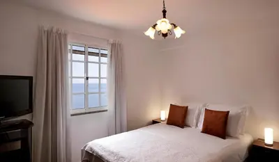 a bedroom with a bed with a window and a chandelier at Taste of the Sea by Formosa in Funchal