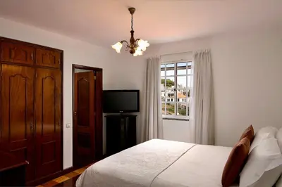 a bedroom with a bed and a television and a chandelier at Taste of the Sea by Formosa in Funchal