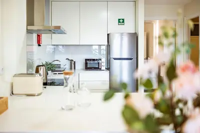 a kitchen with white cabinets and a stainless steel refrigerator at Hidden Corner by Sabugo House in Ponta do Sol