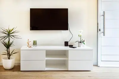 a white desk with a tv on a wall at Hidden Corner by Sabugo House in Ponta do Sol