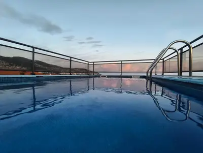 a swimming pool with a bridge and the water at Madalenas Sun&Sea in Funchal