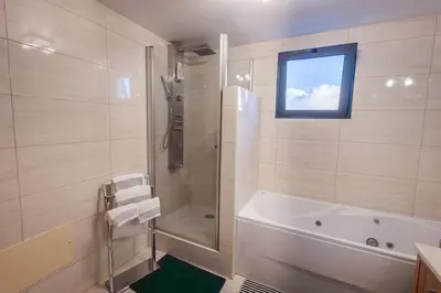 a bathroom with a tub and a shower with a window at Madalenas Sun&Sea in Funchal