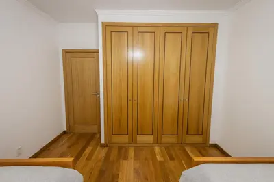 a bedroom with two beds and a wooden closet at Madalenas Sun&Sea in Funchal