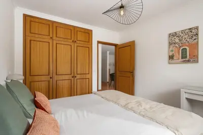 a bedroom with a white bed and a wooden closet at Apartamento da Silva by An Island Apart in Funchal