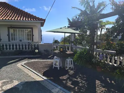 a table with an umbrella in front of a house at Casa Sequeira in Fajã da Ovelha