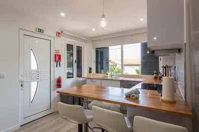 a kitchen with a wooden table and white chairs at Abreu's Place in Câmara de Lobos