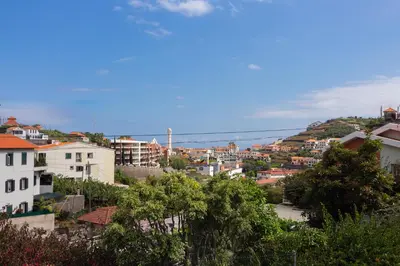 a pink house with a table and chairs and an umbrella at Abreu's Place in Câmara de Lobos