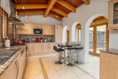 a kitchen with wooden cabinets and a island with bar stools at Peaceful and lovely retreat with a pool #1982 in Barão de São Miguel