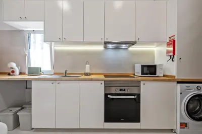 a kitchen with white cabinets and a sink and a stove at Rumo by KAAMAH in Ribeira Brava