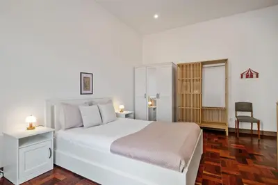 a white bedroom with a white bed and a chair at Rumo by KAAMAH in Ribeira Brava