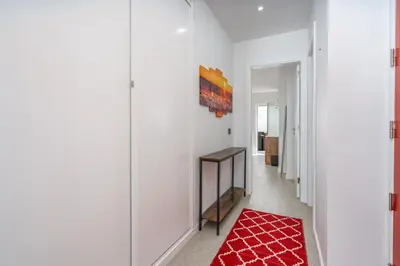 a hallway with white walls and a red rug at Aurazul Apartment in Luz