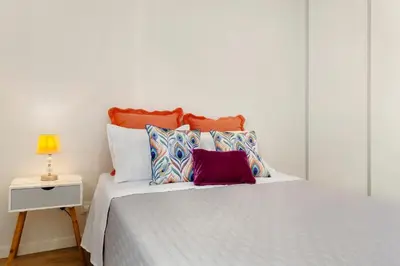 a white bed with colorful pillows on it at Moradia Centro Da Cidade Funchal in Funchal