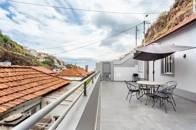 a balcony with a table and chairs and an umbrella at Moradia Centro Da Cidade Funchal in Funchal