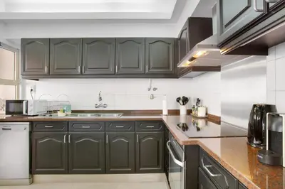 a kitchen with dark green cabinets and a sink at Funchal Centre Bliss -Soulful Stays in Funchal
