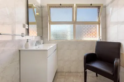 a bathroom with a chair and a sink and a window at Funchal Centre Bliss -Soulful Stays in Funchal