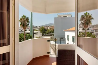 a balcony with palm trees and a view of a city at Funchal Centre Bliss -Soulful Stays in Funchal