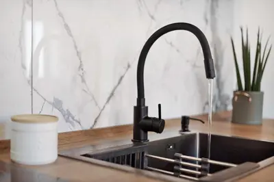 a kitchen sink with a faucet and a cup of coffee at Seaside Haven - Soulful Stays in Porto Moniz