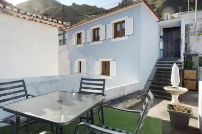 a table and chairs on a patio with a building at Seaside Haven - Soulful Stays in Porto Moniz